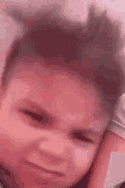 a close up of a child 's face with a pink background making a funny face .