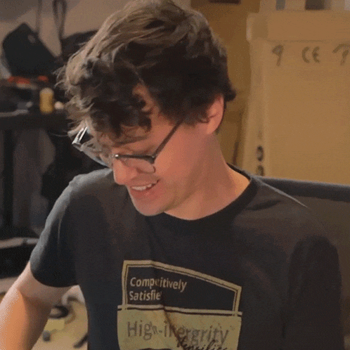 a man wearing glasses and a black shirt that says outrageous on it