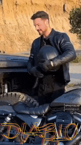 a man in a leather jacket is holding a helmet next to a motorcycle with the word diablo on the side