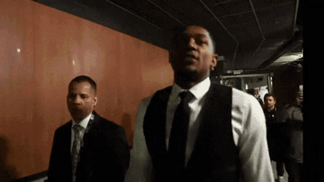 a man in a suit and tie walks down a hallway