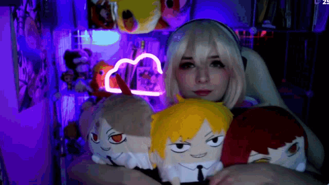 a girl in a wig is surrounded by stuffed anime characters