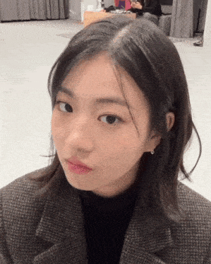 a close up of a woman 's face with a plaid jacket and earrings
