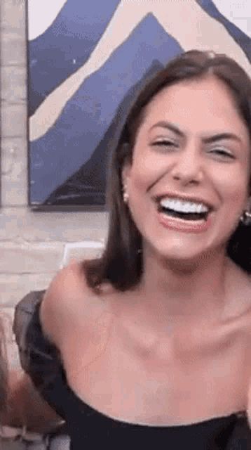 a woman in a black top is laughing with her mouth open