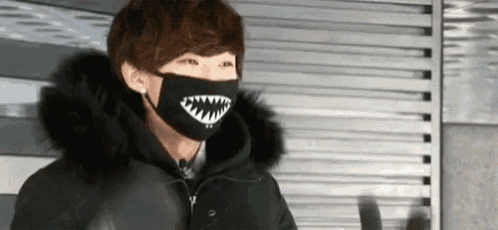 a man wearing a black face mask with a shark face on it .