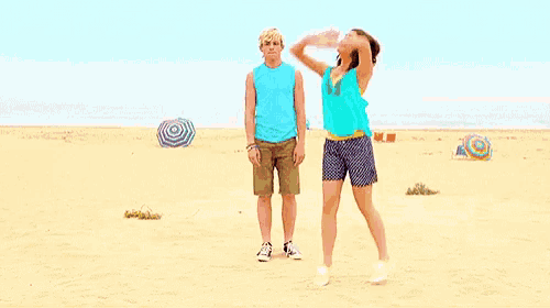 a man and a woman are standing on the beach .