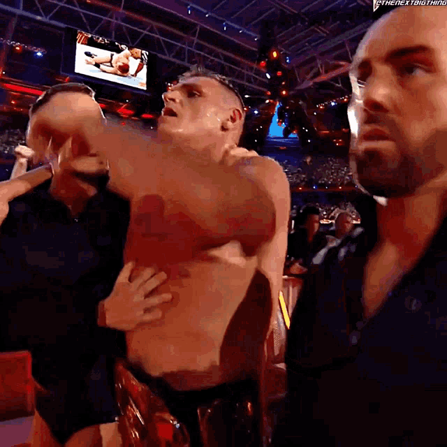 a man without a shirt is being held by a man in a black shirt with the next thing written on the bottom