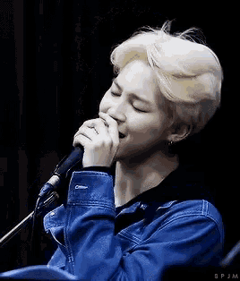 a man with blonde hair is singing into a microphone