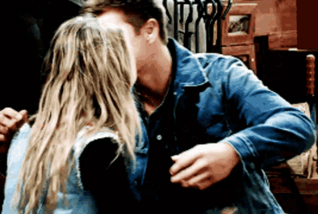 a man in a denim jacket kisses a woman