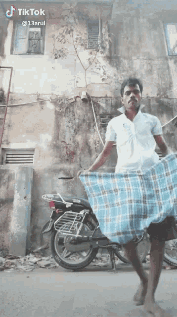 a man wearing a blue and white plaid skirt is standing in front of a motorcycle and a building ..