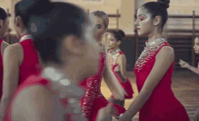 a group of young girls in red dresses are standing in a room