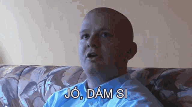 a bald man is sitting on a couch with the words jo dám si above him