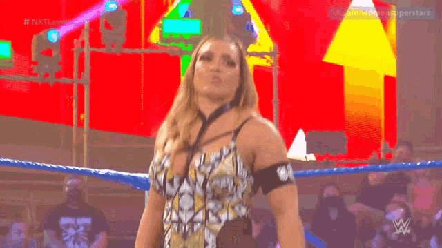 a woman is standing in a wrestling ring with the letters w on the bottom right