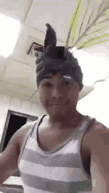 a man wearing a striped tank top and a hat with bunny ears on his head