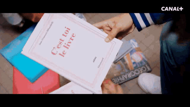 a person is holding up a book that says c'est toi le livre