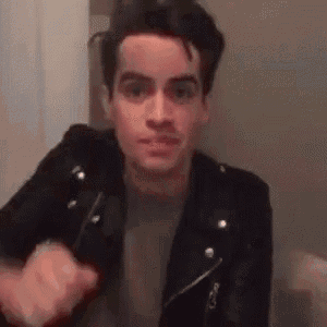 a man in a black leather jacket is holding a knife and making a face .