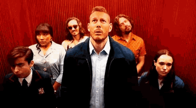 a group of people are standing in an elevator looking up at the camera .