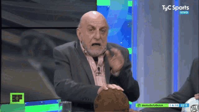 a man holds a soccer ball in front of a tv screen that says tyc sports vivo