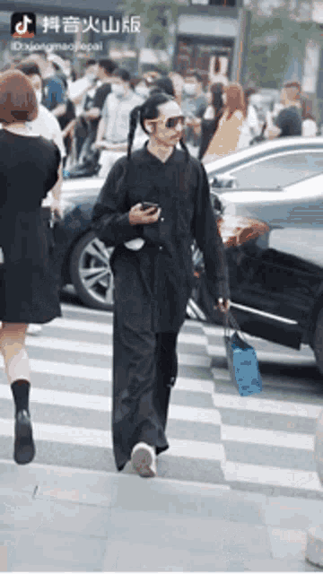a man in a black outfit is walking down the street