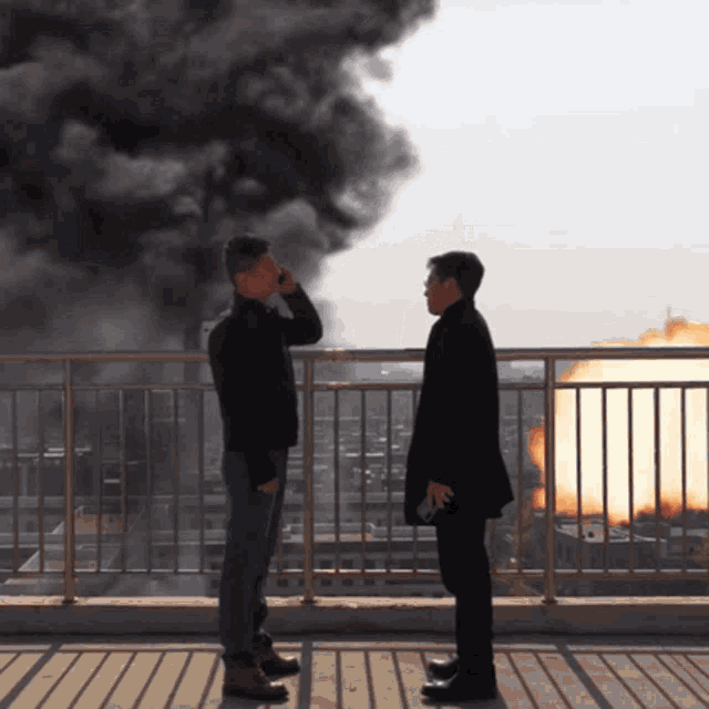 two men standing on a balcony with smoke coming out of a building
