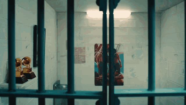 a jail cell with a painting on the wall and a trophy on a shelf