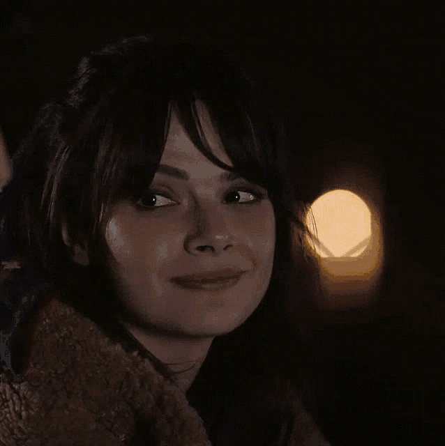 a close up of a woman 's face in the dark with a light behind her