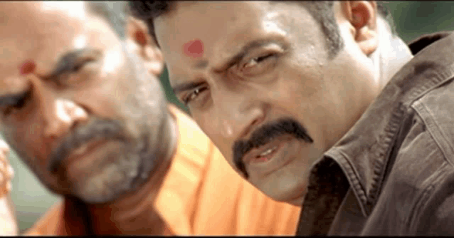 a man with a mustache has a red dot on his forehead .