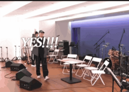 a man is standing in front of a microphone with the words yes written on the screen