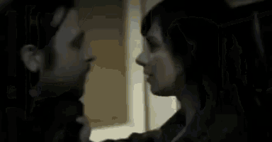 a woman is hugging a man in a dark room .