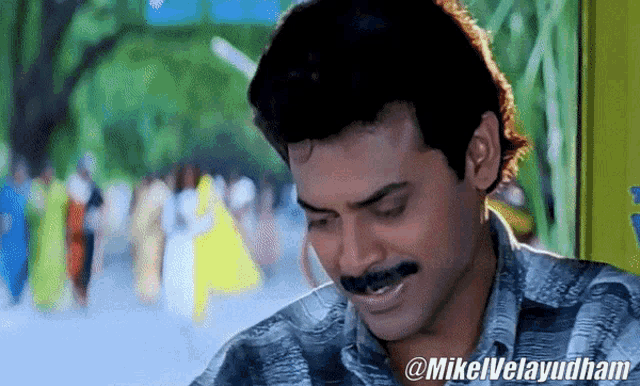 a close up of a man with a mustache and the name mikelvelayudham on the bottom right