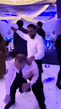 a man in a tuxedo is dancing with another man in a white shirt