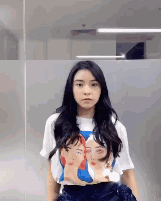 a young woman wearing a t-shirt with three faces on it .