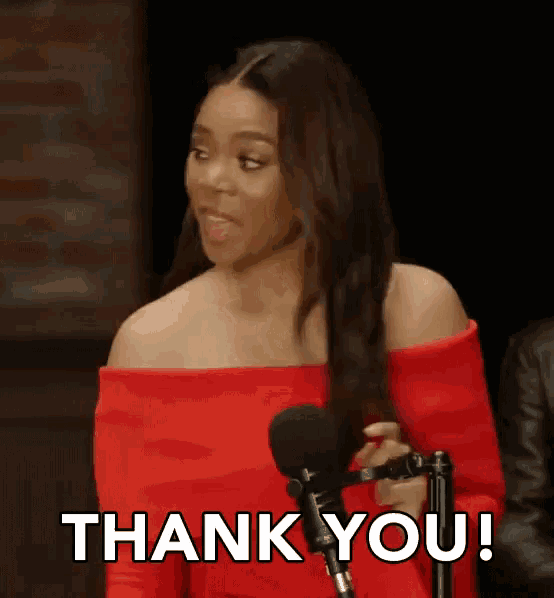 a woman in a red dress is standing in front of a microphone and says thank you !