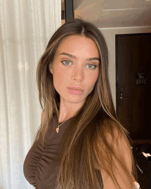 a woman in a brown top is standing in front of a door that says chanel