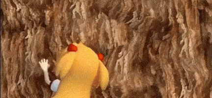a yellow teddy bear is crawling up a rock wall .