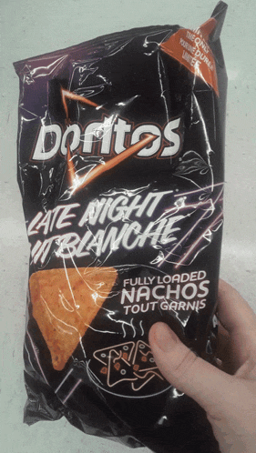 a person is holding a bag of doritos late night blanche nachos