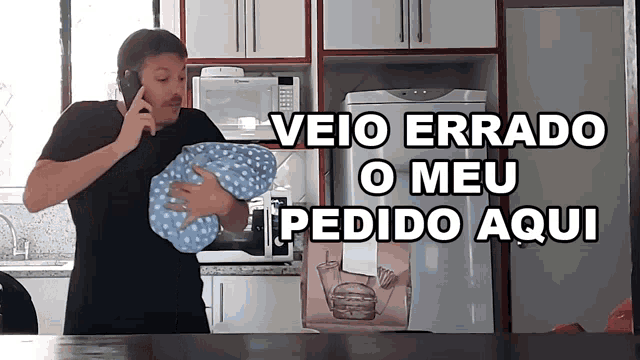 a man talking on a cell phone in a kitchen with veio errado o meu pedido aqui written on the bottom