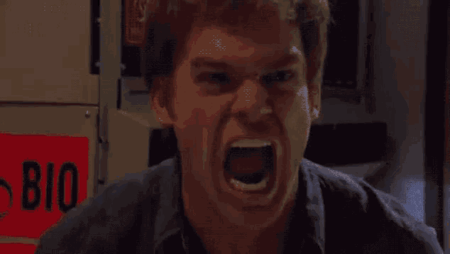 a close up of a man 's face with his mouth open and a red sign in the background .