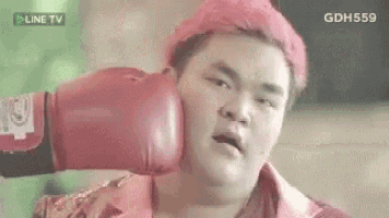 a man with red hair is wearing red boxing gloves and getting a punch in the face .
