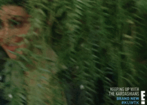 a woman peeking out from behind a tree with the words keeping up with the kardashians