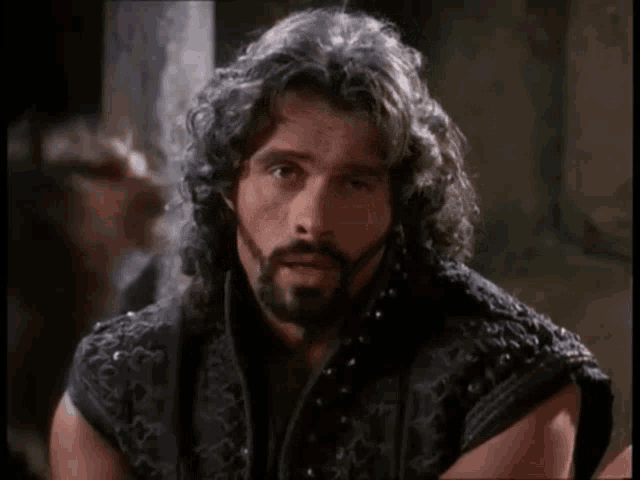 a man with long hair and a beard is looking at something