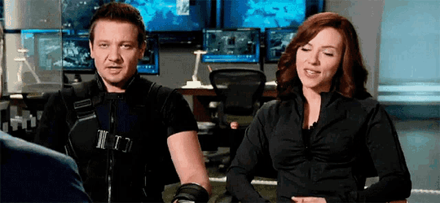 a man and a woman are sitting next to each other in front of a computer monitor .