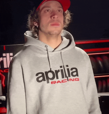 a man wearing a grey aprilia racing sweatshirt