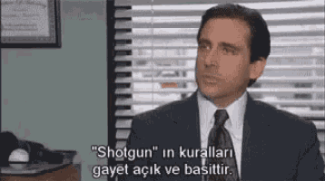 a man in a suit and tie is sitting in front of a window and talking in a foreign language .