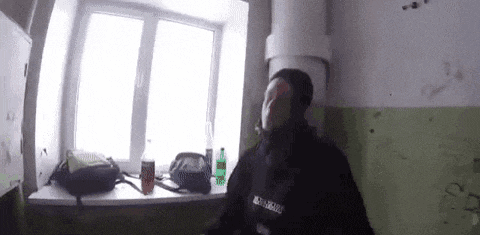 a man is sitting on a window sill in front of a window in a room .