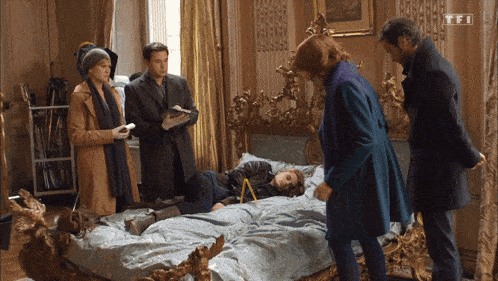 a group of people are looking at a woman laying on a bed with a tf1 logo on the bottom