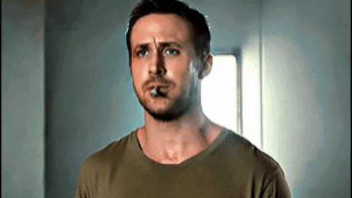 a man in a green shirt is smoking a cigarette and making a funny face .