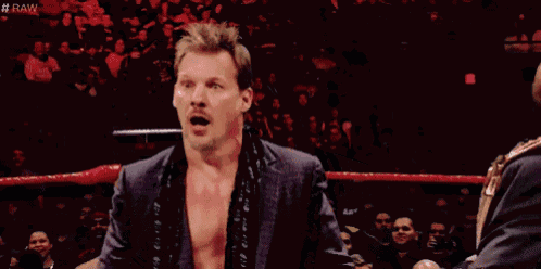 a man in a suit is standing in a wrestling ring with his mouth open and a surprised look on his face .