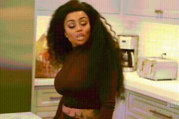 a woman is standing in a kitchen wearing a purple crop top .