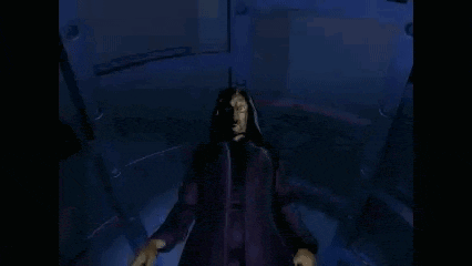 a man is sitting in a dark room with his hands outstretched .