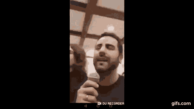 a man is holding a microphone in front of his face and smiling .